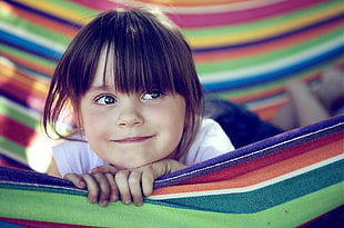 girl smiles while lying in multicolored hammock